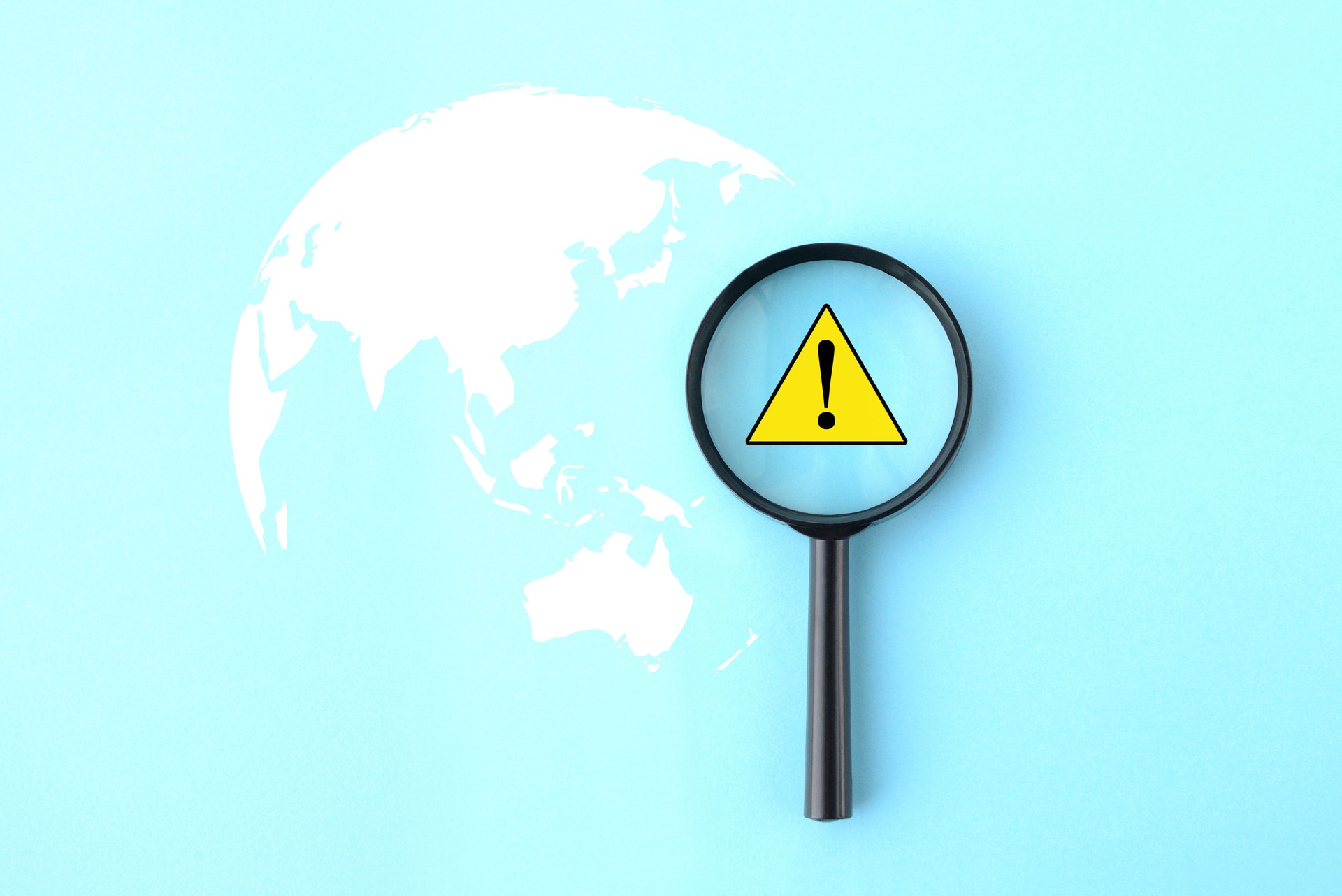 Earth silhouette and magnifying glass with warning mark